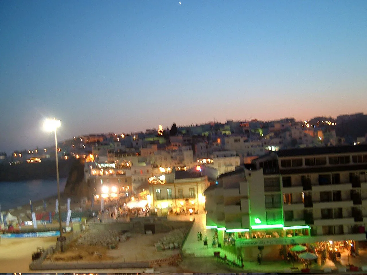 Albufeira old town lit up in the evening, seen from the beach hill.