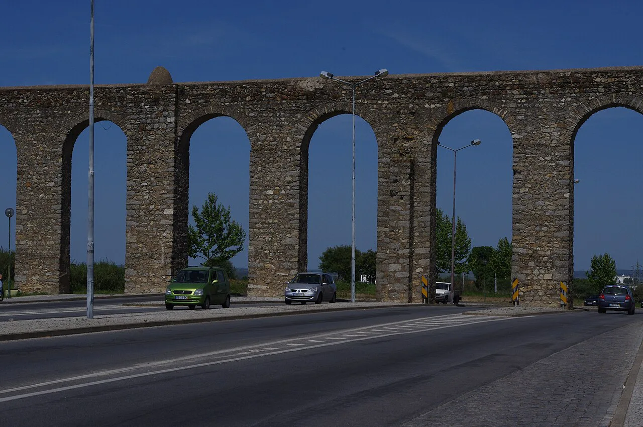 The arches of the Aqueduct of Silver Water spanning a road in Évora.