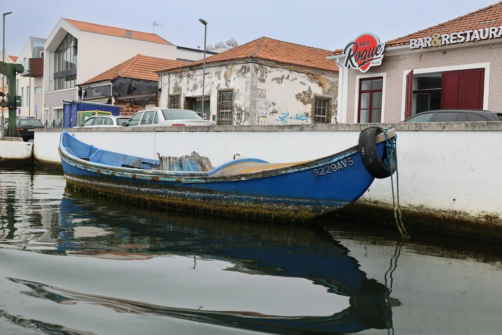 A blue moliceiro boat moored on a canal in Aveiro.
