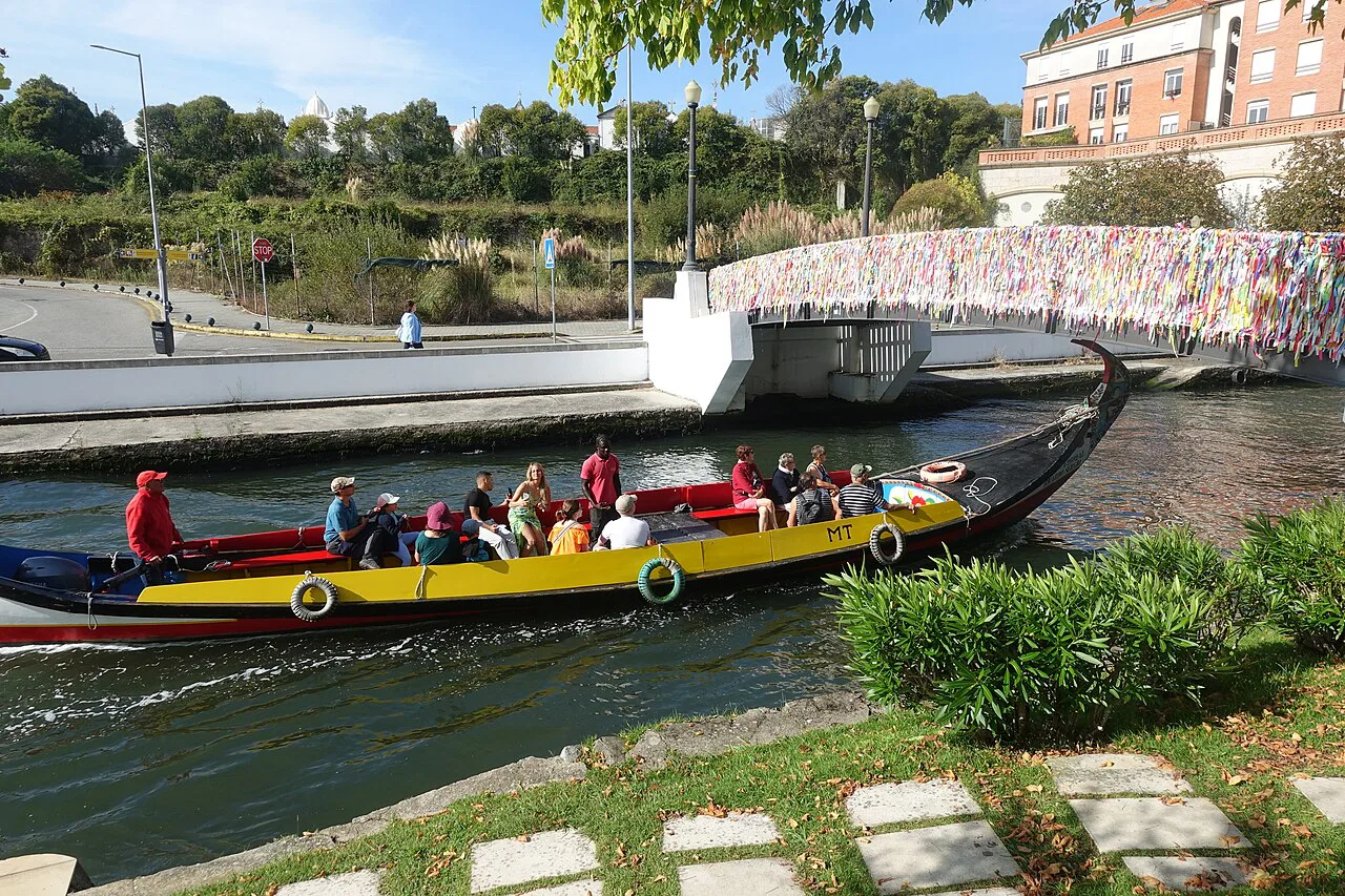 A moliceiro boat on the Canal do Cojo in Aveiro, passing a bridge.