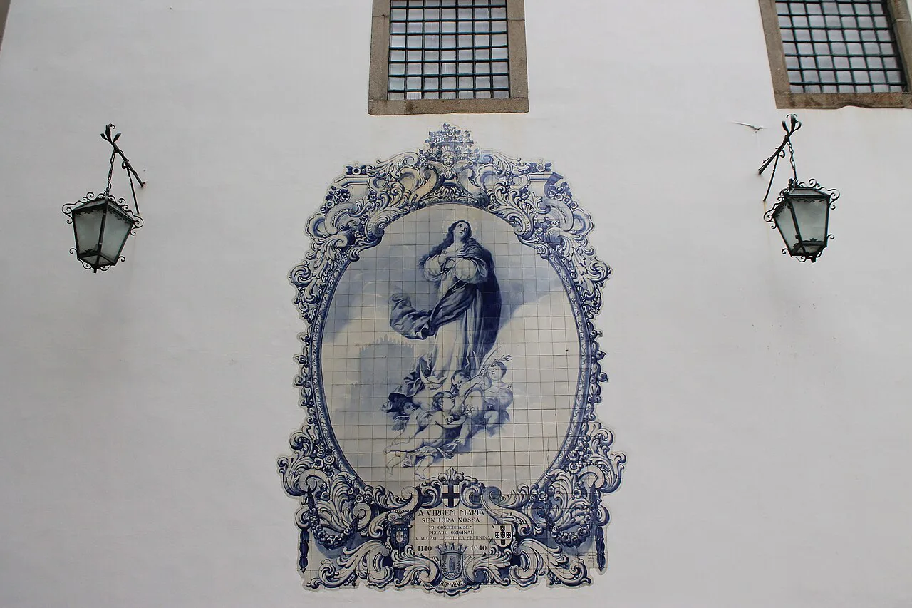A blue and white azulejo panel of the Virgin between two street lamps in Guimarães.