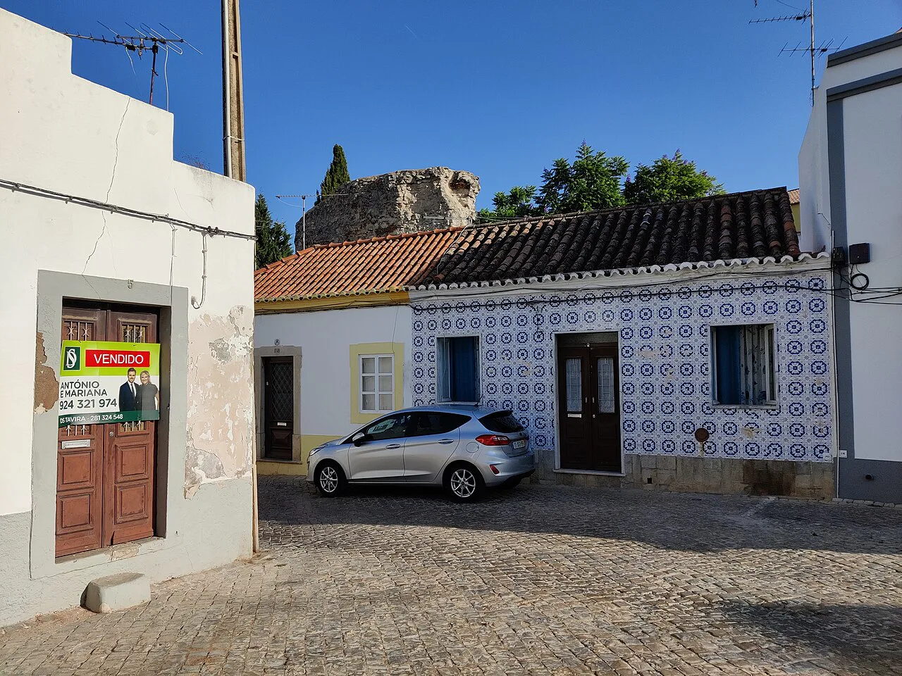 A house front clad in patterned blue-and-white tiles below the castle walls in Tavira.
