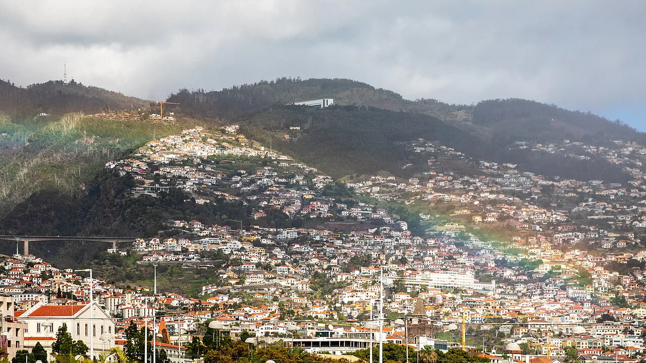 Funchal spread across the hillside, with a rainbow in the drizzle.