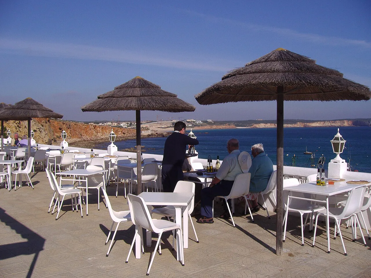 The outdoor patio of the restaurant A Tasca in Sagres, with parasols overlooking the sea.