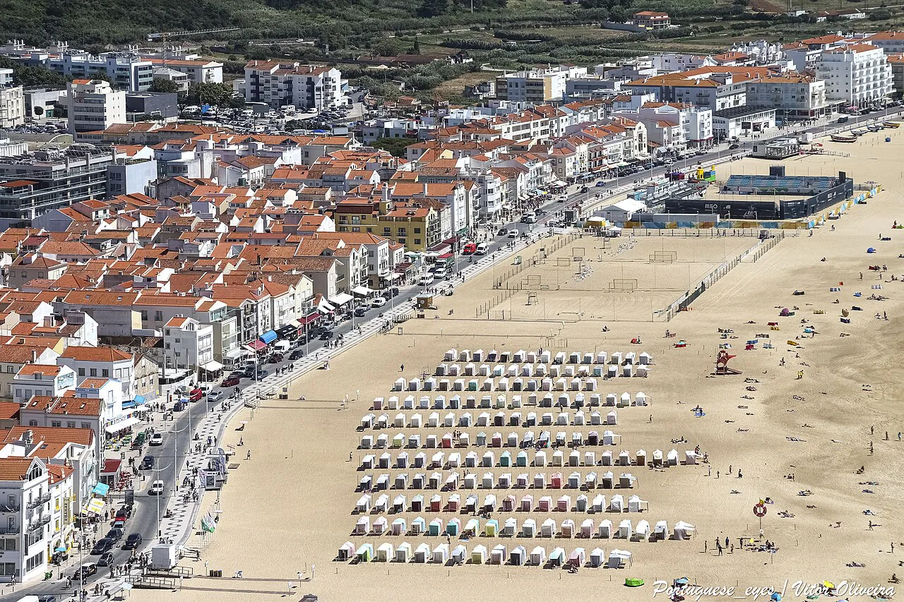 An aerial view of Nazaré beach lined with rows of beach tents.