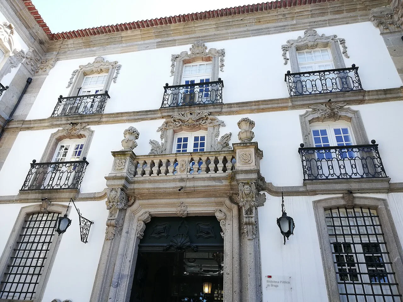 A carved doorway and iron balconies on the façade of the Paço Episcopal in Braga.