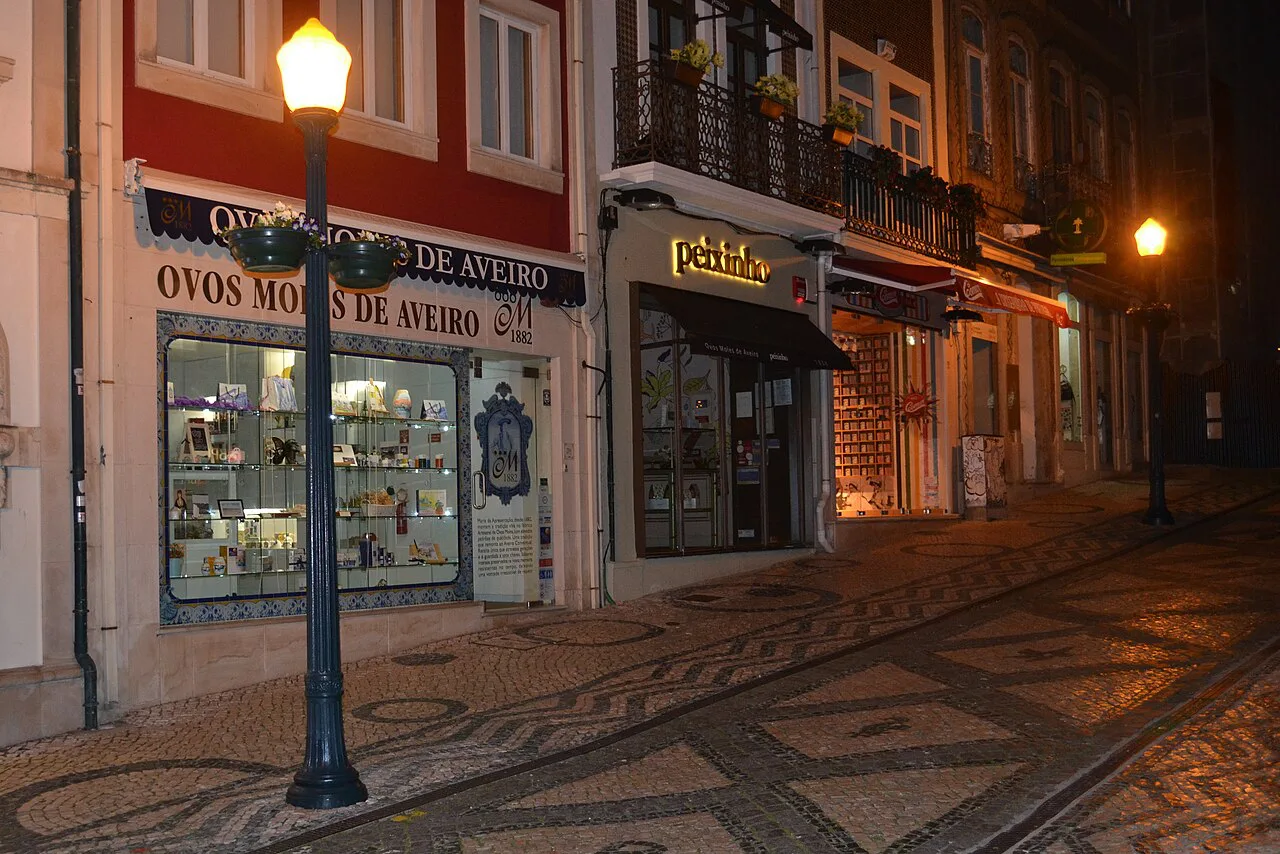 A shop selling ovos moles on a street in Aveiro at night.