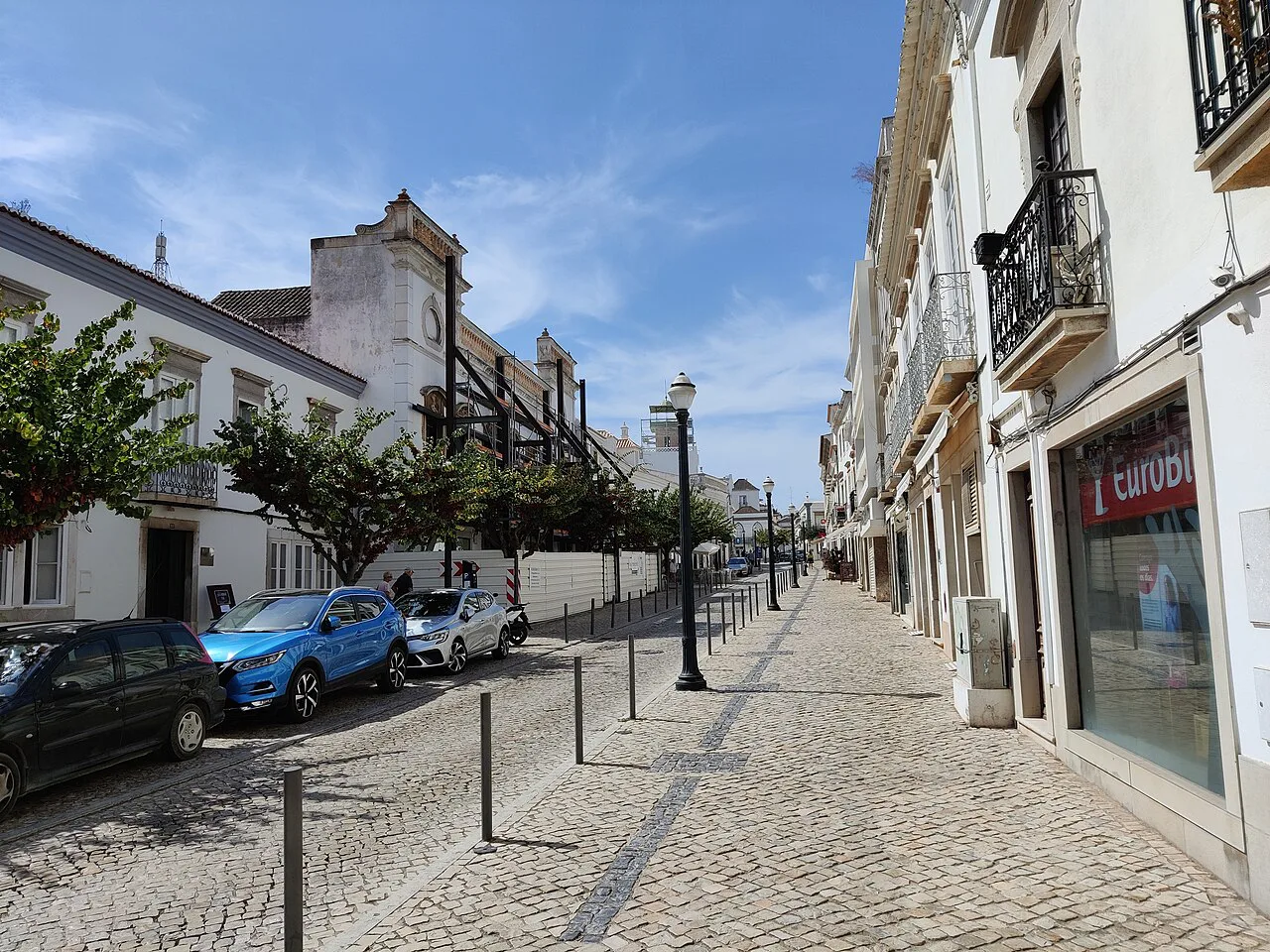 A cobbled shopping street lined with white buildings in Tavira.
