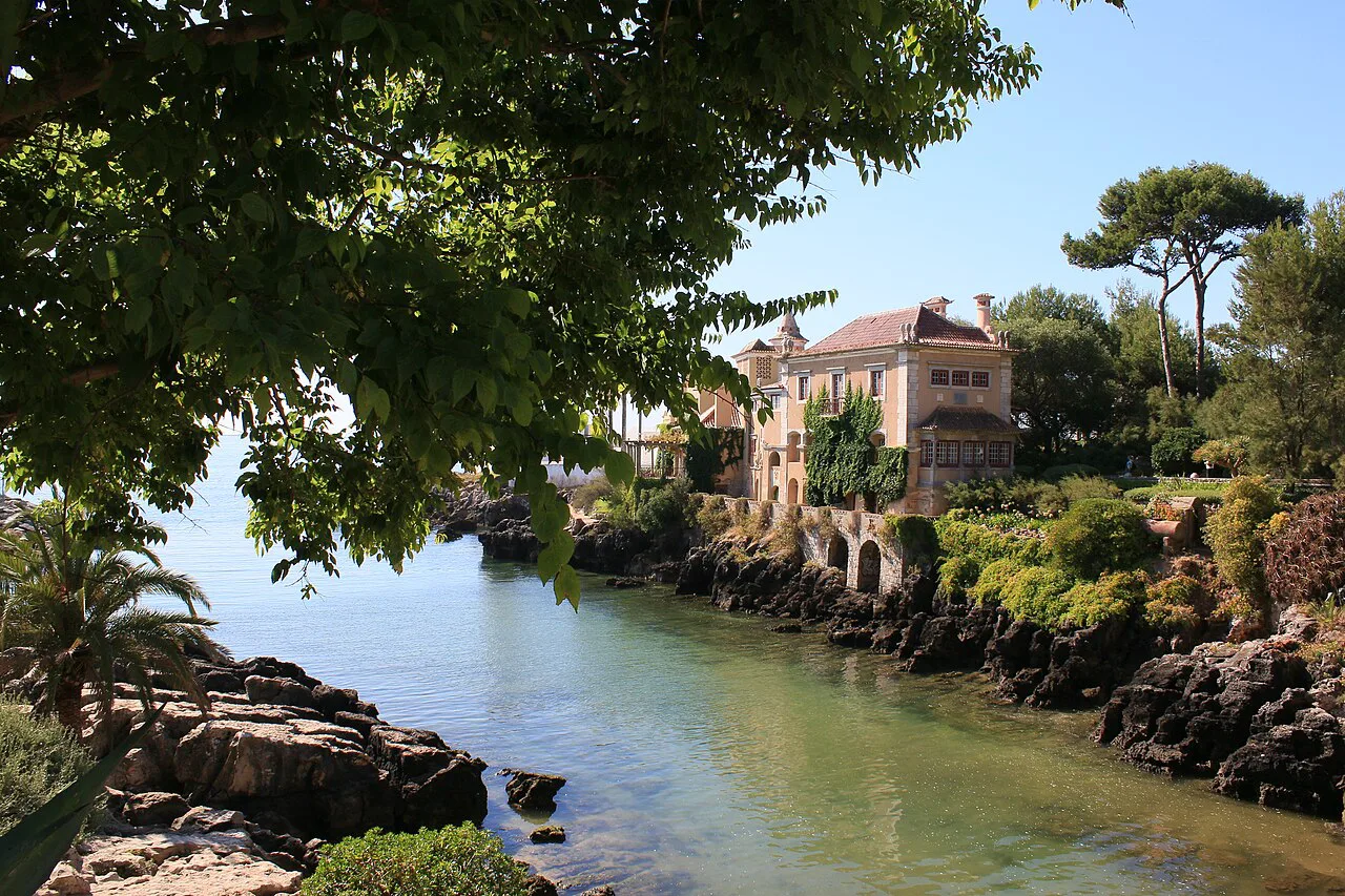 A rocky inlet and waterside houses in Cascais at low tide.