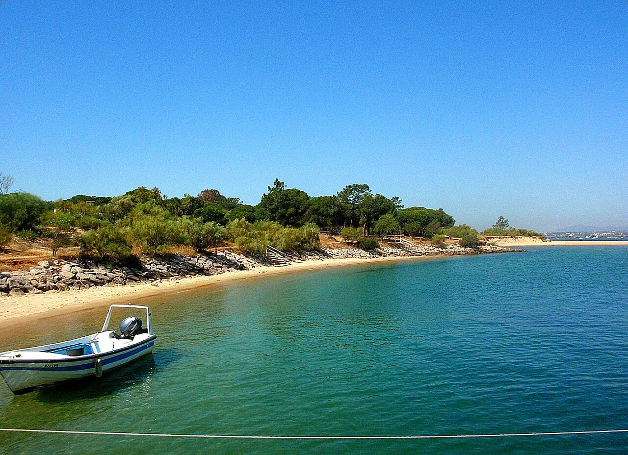 A small boat on the calm water beside the shore of Tavira Island.