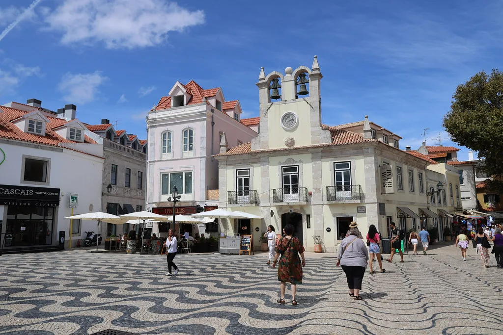 A paved square with wave patterns in front of historic buildings in Cascais.