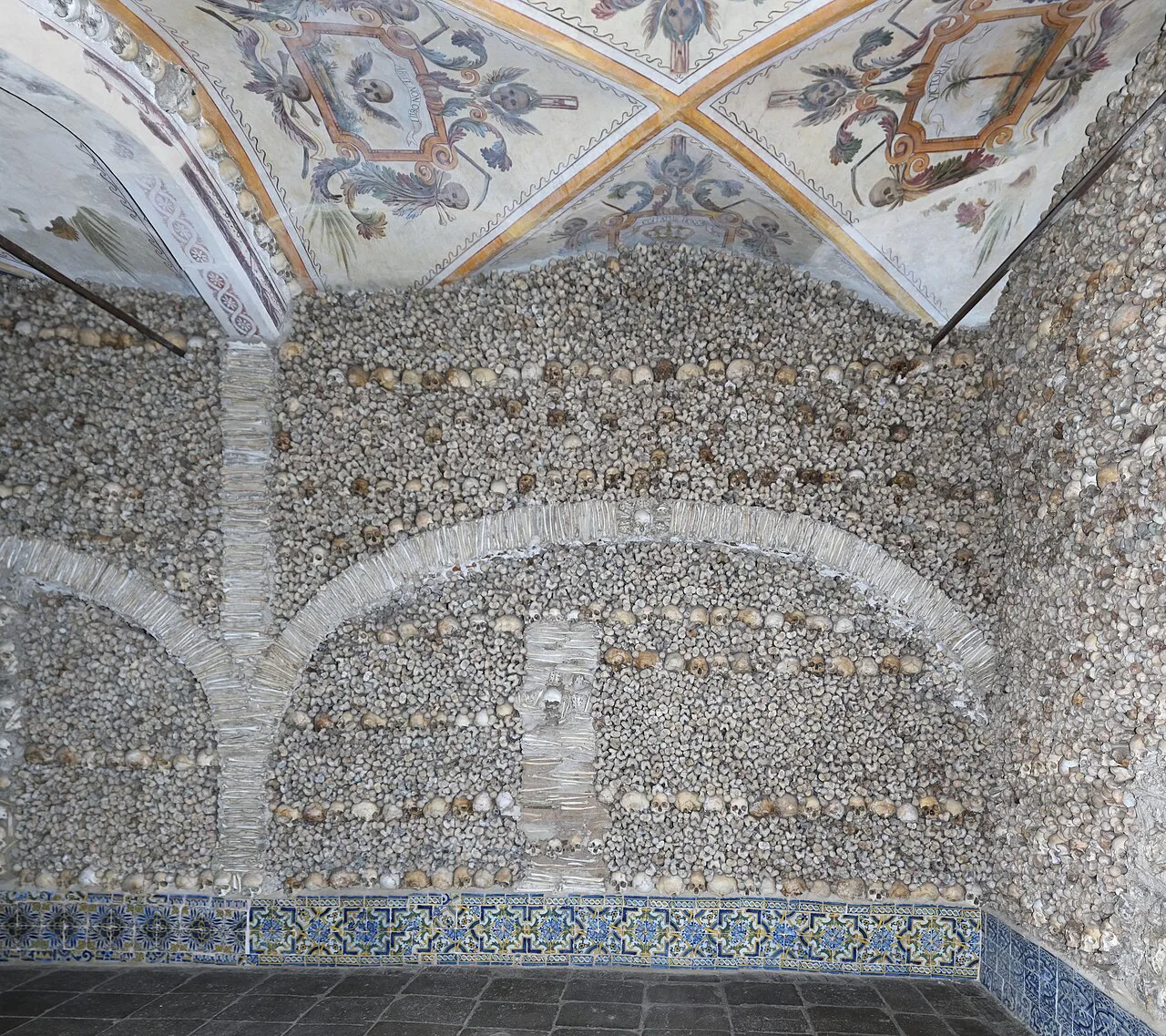 The bone-covered right wall and painted ceiling of the Chapel of Bones in Évora.
