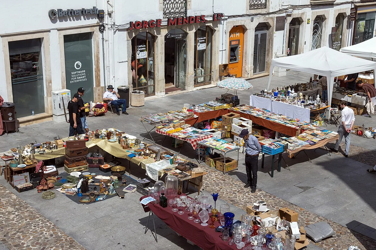 Tables of second-hand goods at the flea market on Praça do Comércio in Coimbra.