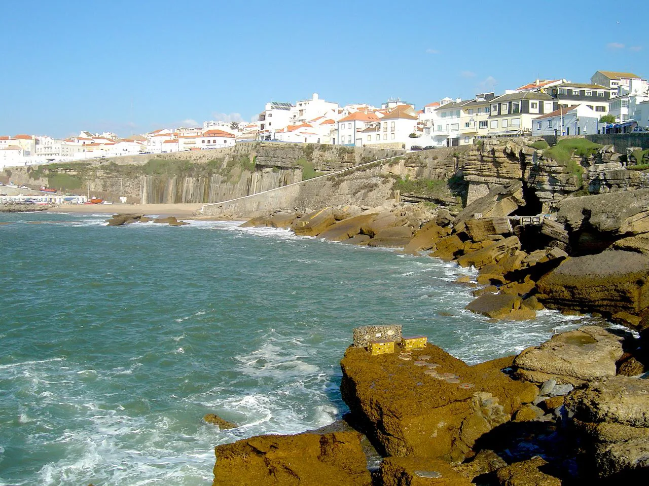 Rocky shoreline below Ericeira's white clifftop houses.