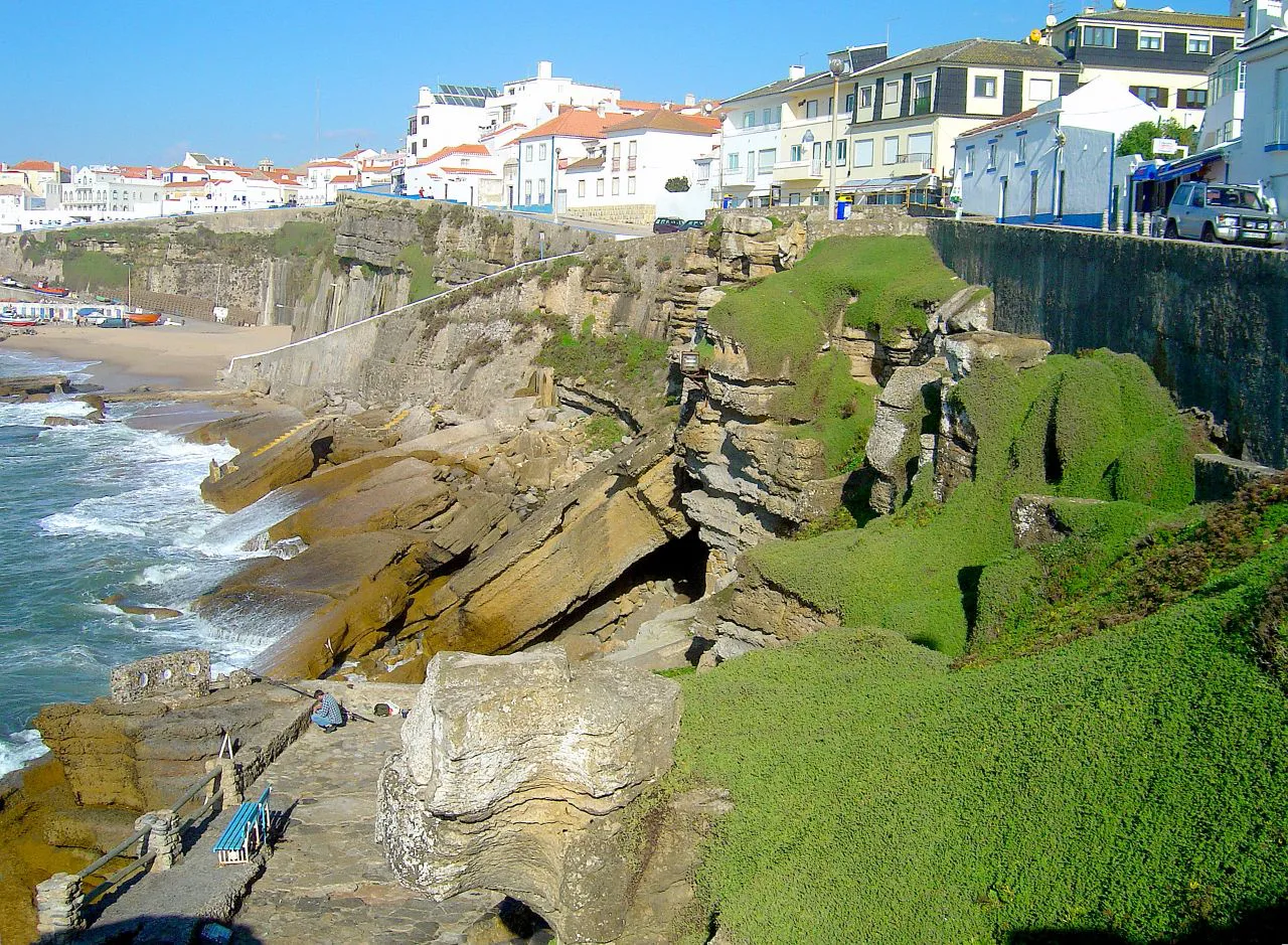 Ericeira's white houses on the clifftop above rocky shore.