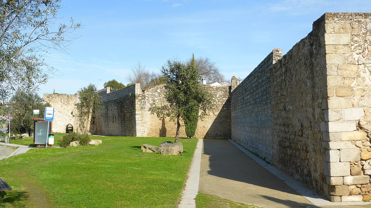 A stretch of the old city walls of Évora beside a lawn.