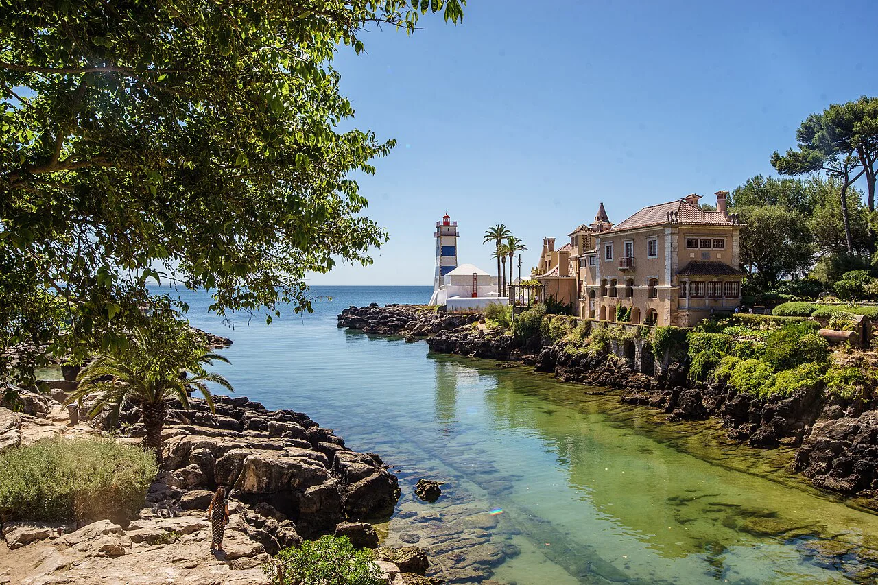 The Farol de Santa Marta seen across a clear inlet on the Cascais coast.