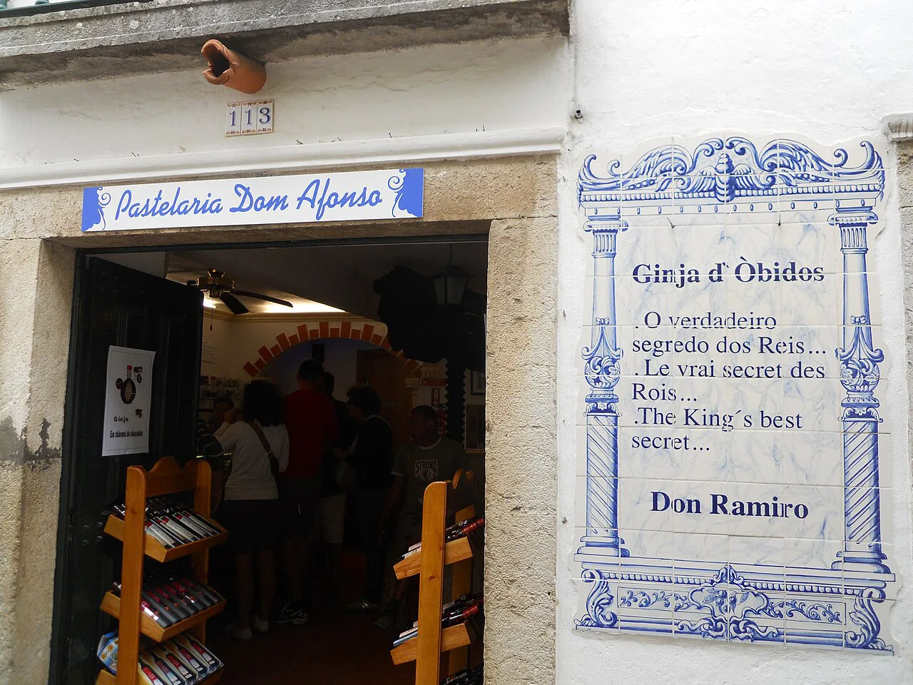 A ginjinha shop in Óbidos with an azulejo sign beside the door.