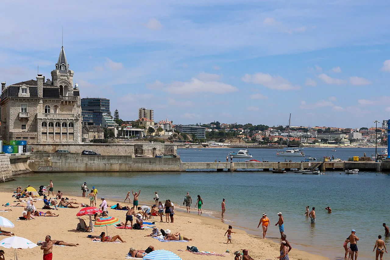 Bathers on a small town beach beside the harbour in Cascais.