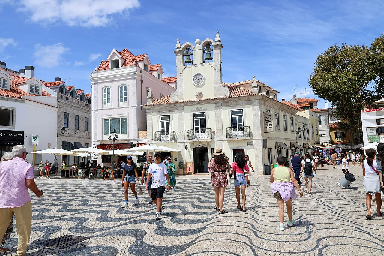 People crossing a calçada-paved square in central Cascais.