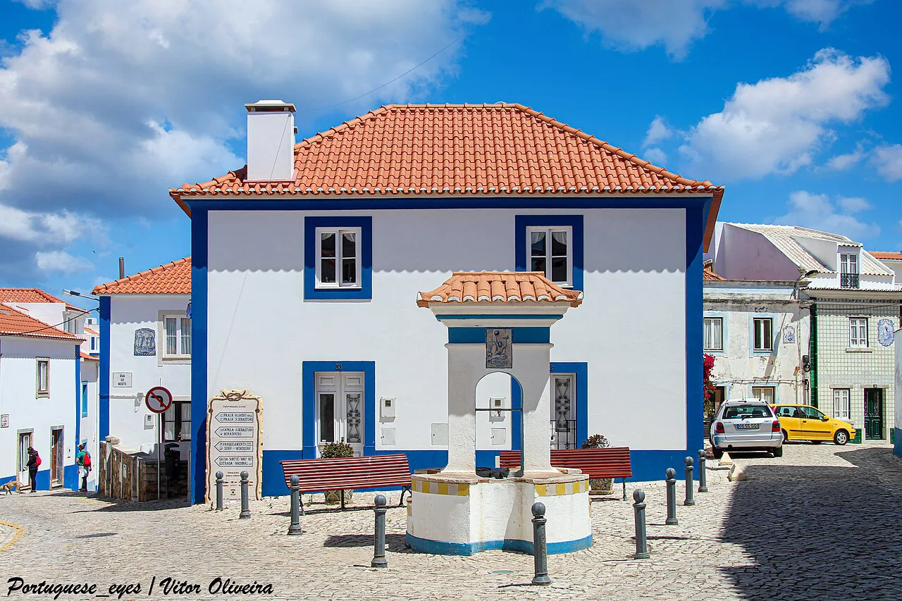 A white and blue house on a cobbled square in Ericeira.