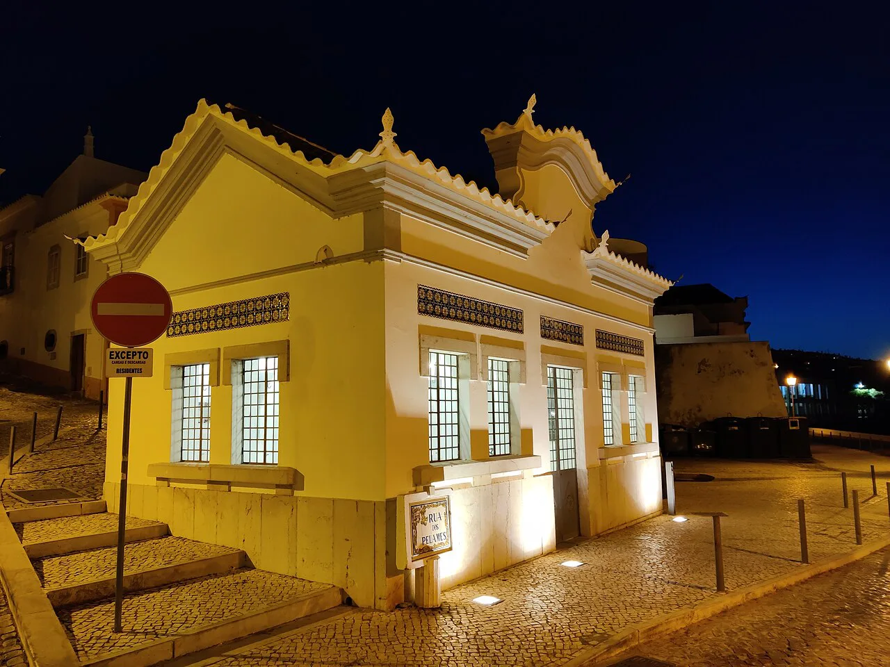 A yellow-painted building lit up at night in Tavira.
