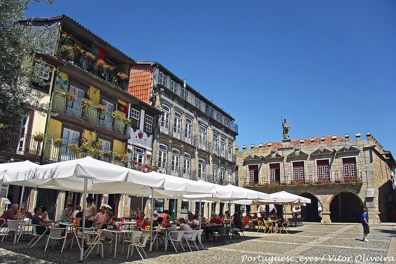 Café terraces under umbrellas on Largo da Oliveira in Guimarães.