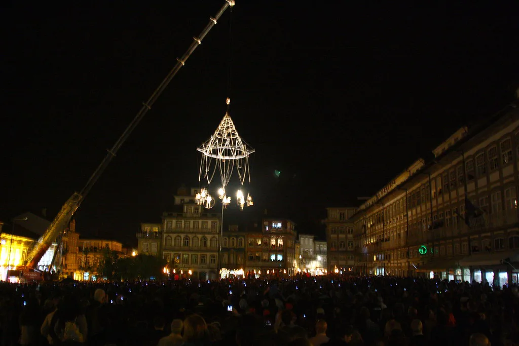 A night aerial performance by Transe Express above a crowd on Largo do Toural in Guimarães.