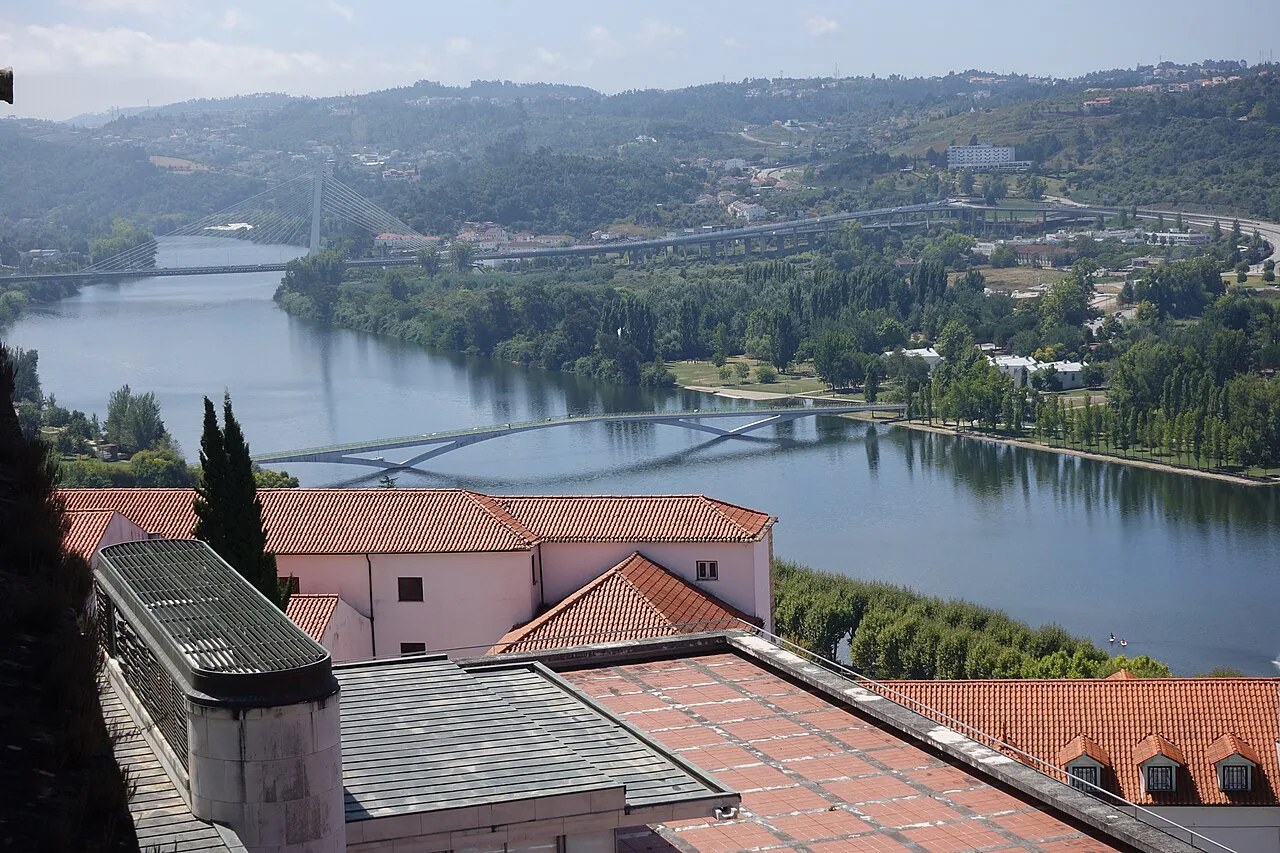 View over Coimbra rooftops to the river and its bridges.