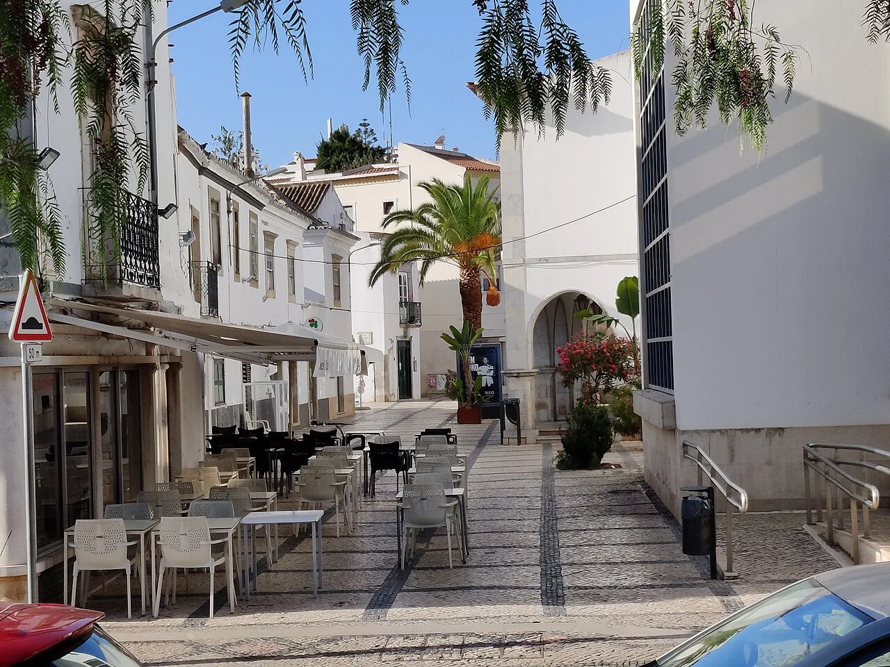 A whitewashed street with café tables in Tavira.