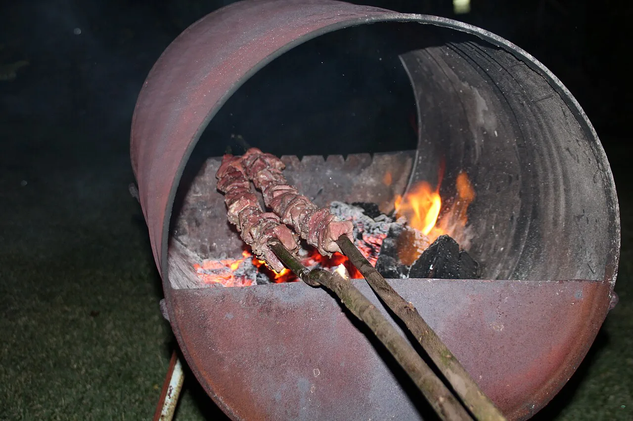 Beef espetada skewers cooking over a barrel grill in Estreito da Calheta, Madeira.