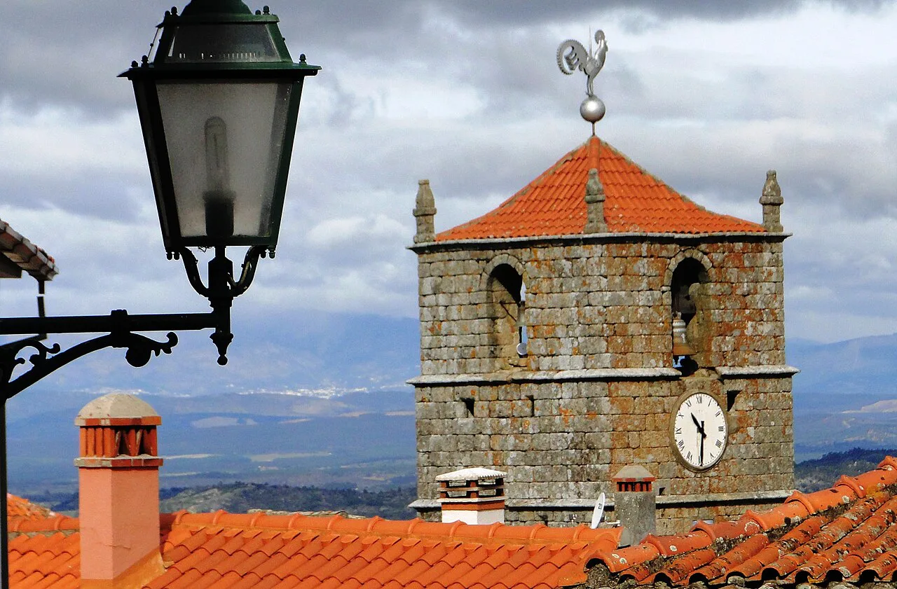A clock tower above the rooftops of Monsanto.
