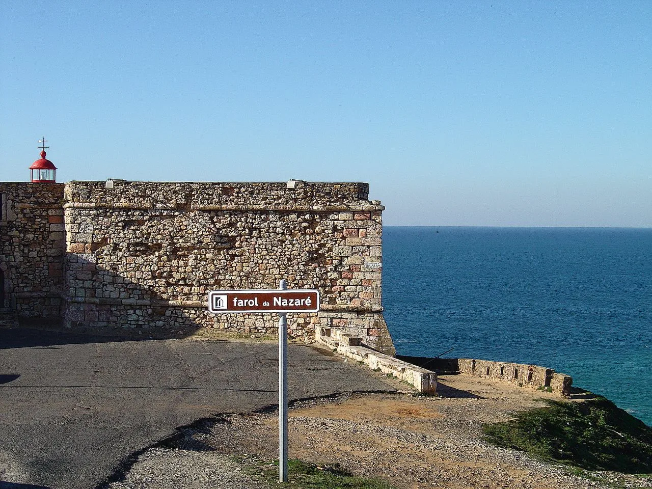 The fort walls and lighthouse of Nazaré above the Atlantic.