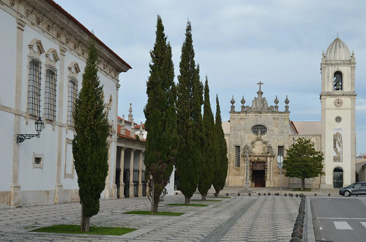 Aveiro Cathedral seen across a square lined with cypress trees.