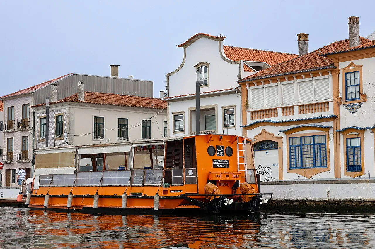 A tour boat on the canal in front of decorated façades in Aveiro.