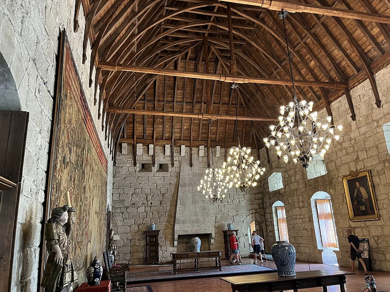 A hall with a wooden ceiling, tapestries and chandeliers inside the Palace of the Dukes of Braganza in Guimarães.