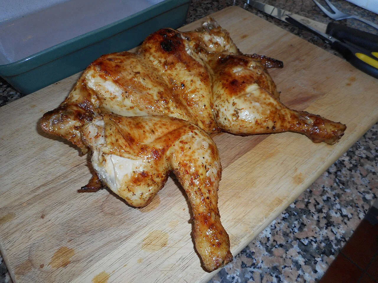 A whole grilled piri piri chicken on a wooden board.