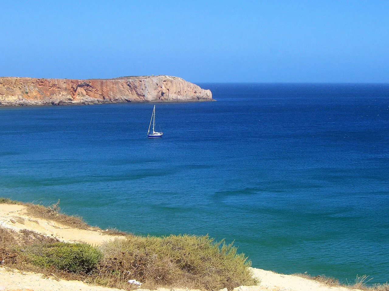 A sailing boat off the cliffs at Ponta da Atalaia, Sagres.