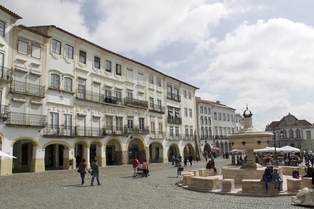 Arcaded buildings and a fountain on a square in Évora's centre.