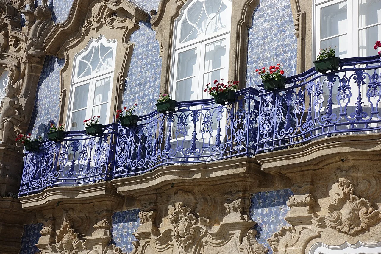 Ornate window surrounds and iron balconies against blue azulejos on the Palácio do Raio in Braga.