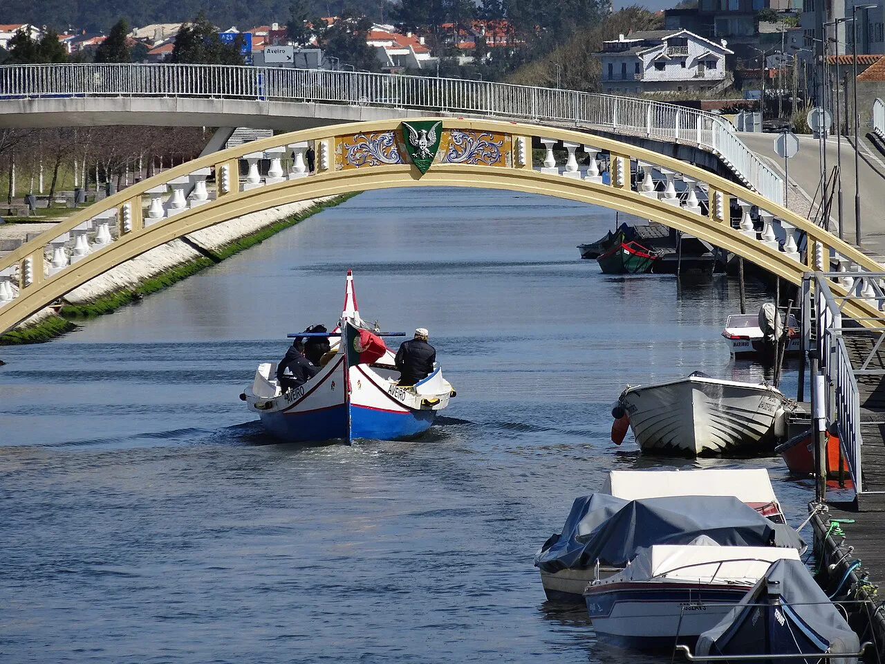 A moliceiro boat passing under a bridge on an Aveiro canal.