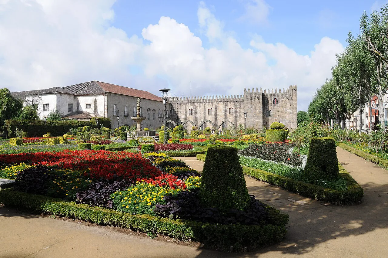Clipped hedges and flowerbeds in the Santa Barbara Garden in Braga, with the medieval palace walls behind.