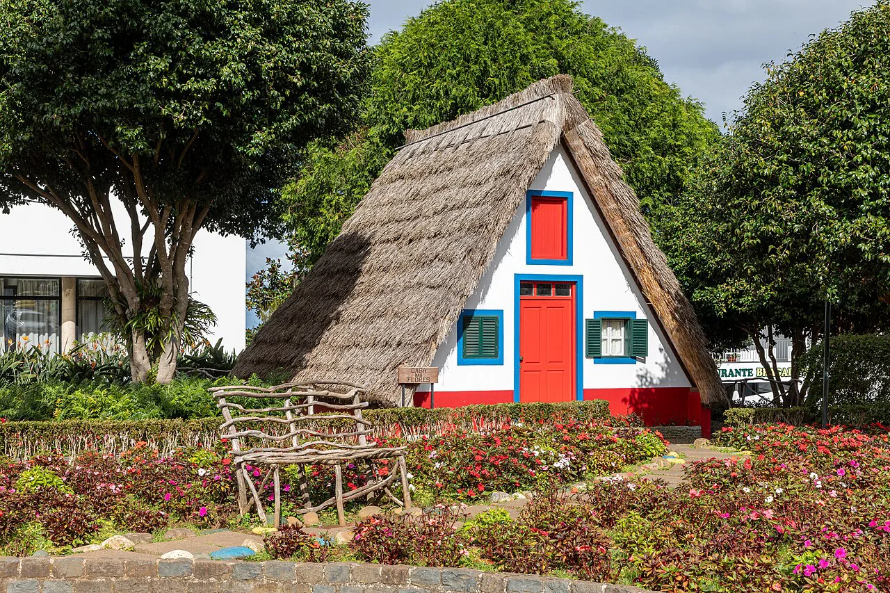 A traditional thatched house among flower beds at the Casas Típicas de Santana in Madeira.