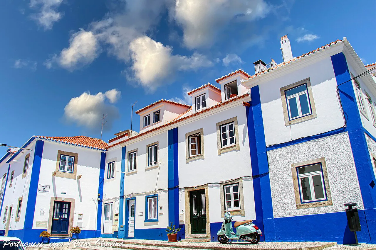 White houses with blue trim on a street in Ericeira.