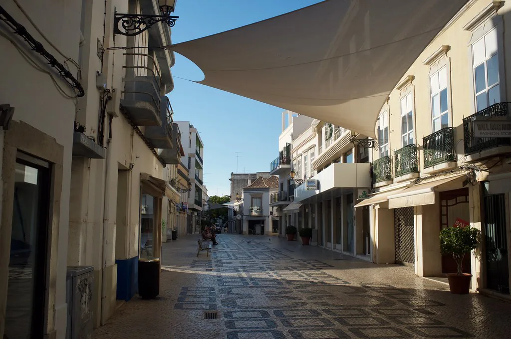 A shaded pedestrian street lined with shops in Faro.