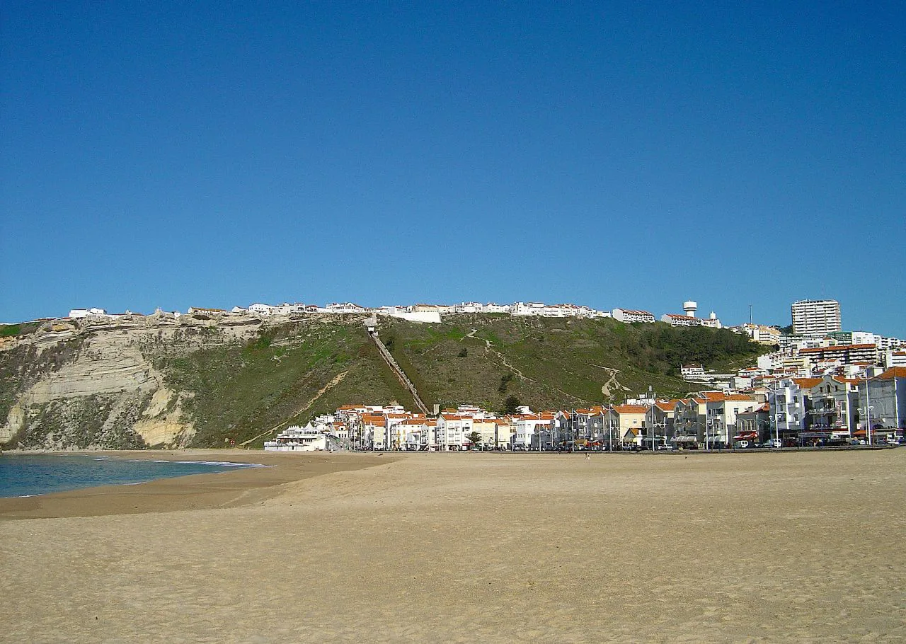 The beach and town of Nazaré beneath a green headland.