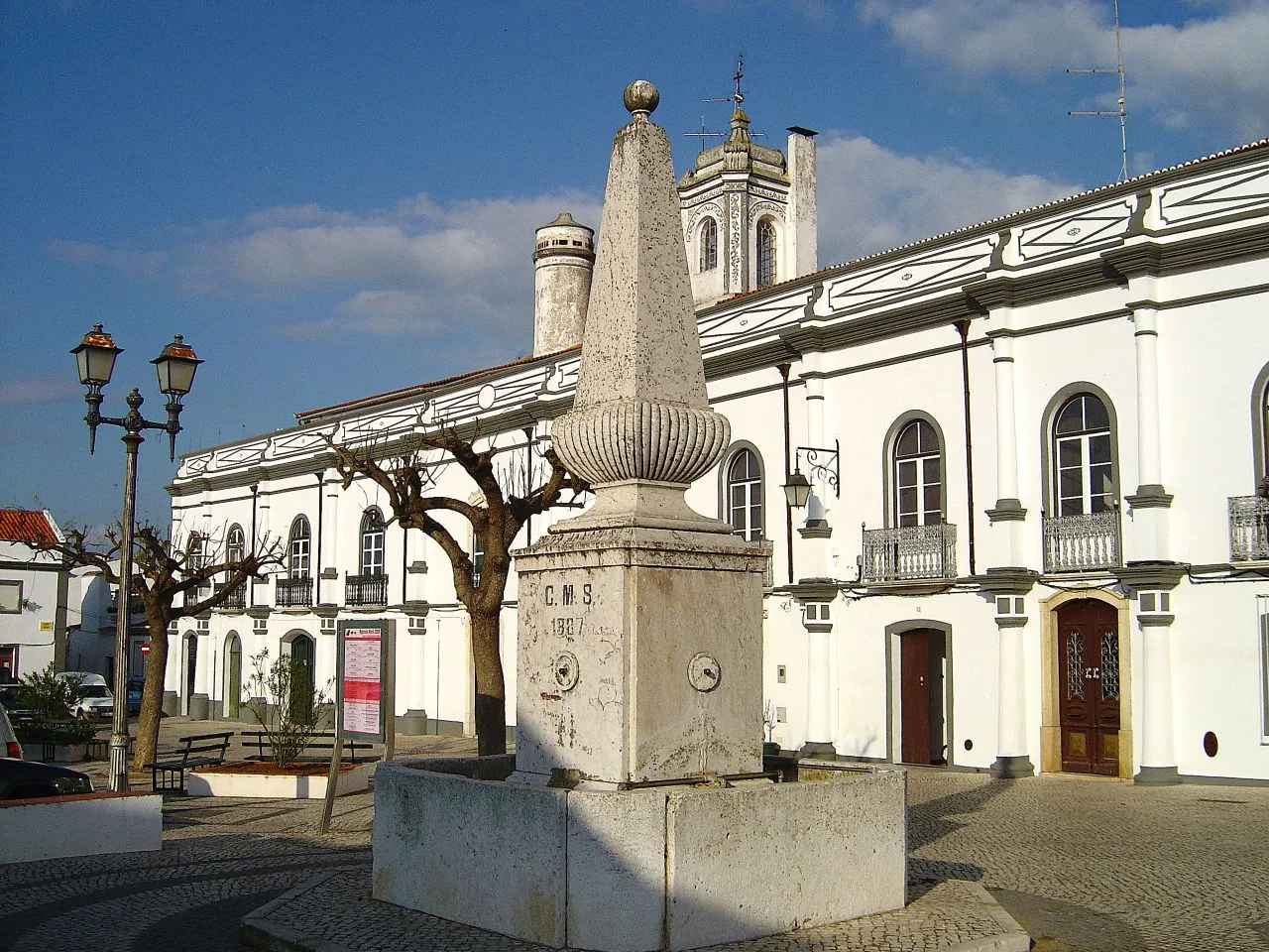 A whitewashed square with a stone pillar in the centre of Serpa.