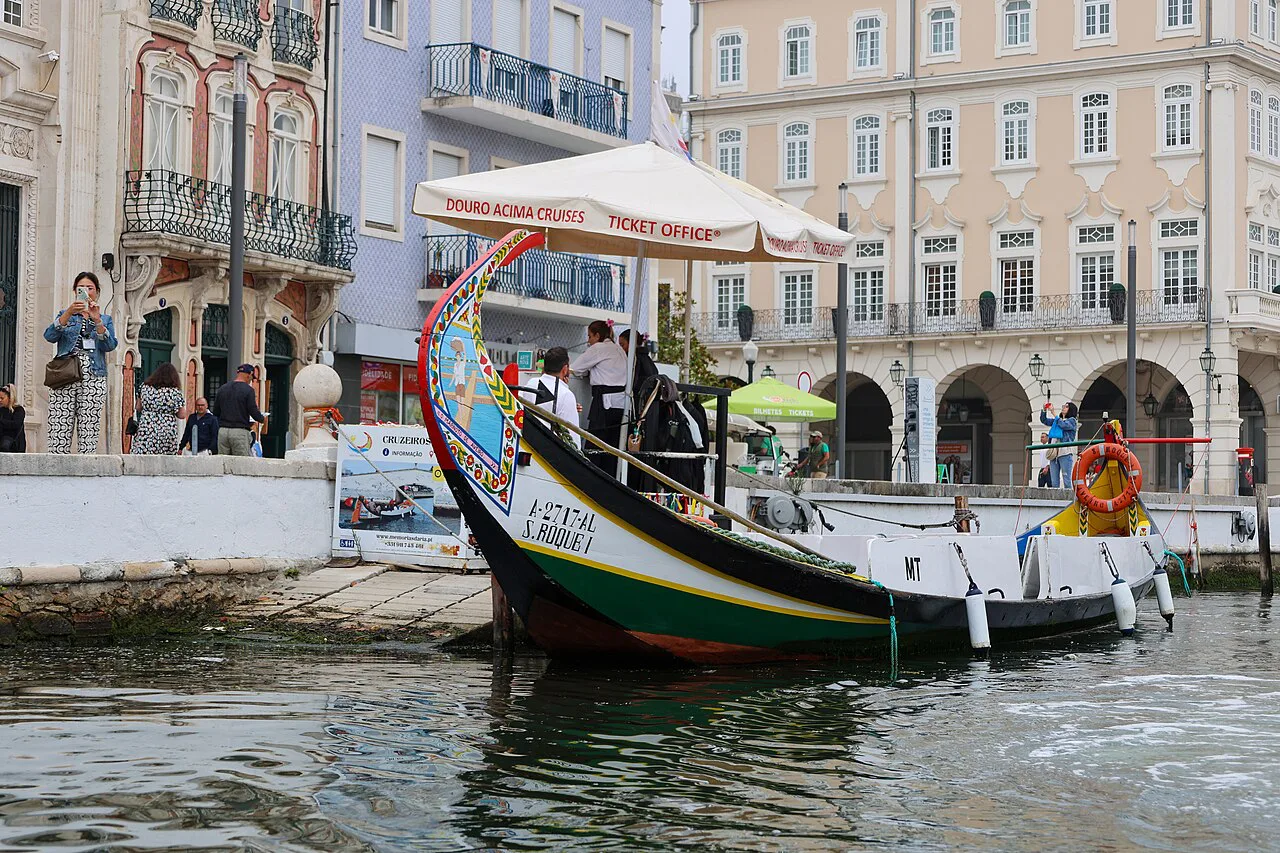 A moliceiro boat moored on a canal in Aveiro, beside buildings in the town centre.