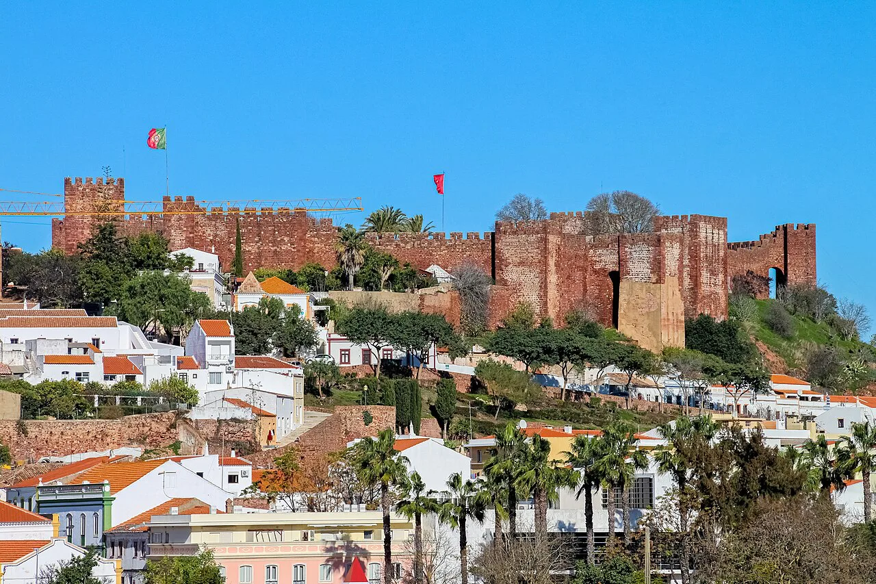 Silves Castle rising above the town's houses and palm trees.