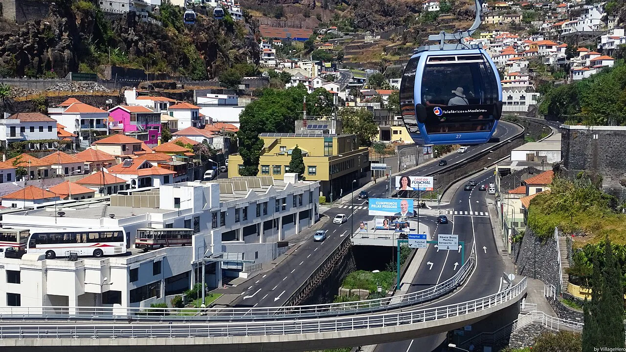 A Funchal cable car cabin passing above the city and its main road.